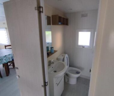Salle de bain avec lavabo toilettes et rangements dans le mobil home 4 couchages