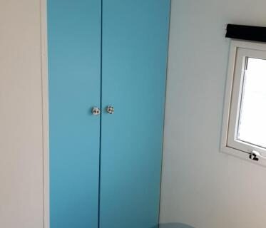 Intérieur de la chambre avec armoire bleue et lit dans le mobil home 4 couchages