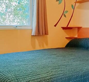 Chambre avec lit et fenêtre donnant sur arbres dans le Mobil-home 4 personnes