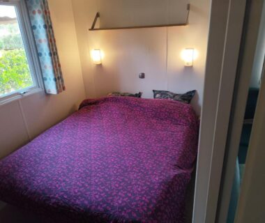 Chambre avec lit double lampes et fenêtre dans le mobil-home Camping Marisol