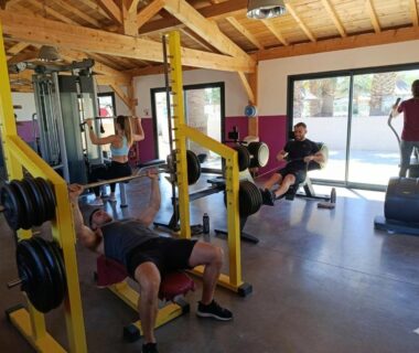 Salle de sport avec banc de musculation et personnes s'entraînant au Mobil-home 4 personnes clim camping Marisol