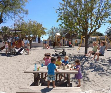 Aire de jeux sablonneuse avec enfants et tables au camping Marisol