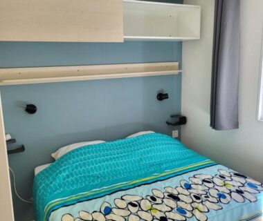 Chambre avec lit double rangements et rideau dans le mobil home 4 personnes climatisé