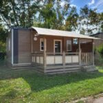 Terrasse en bois couverte et pelouse autour du mobil home 4 personnes climatisé