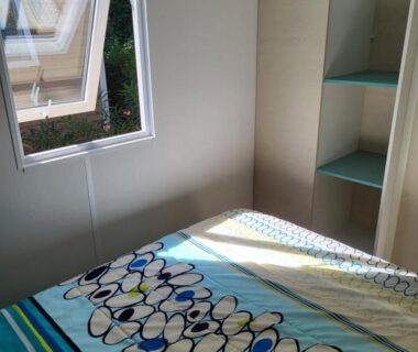 Chambre avec lit et rangements ouverts dans le mobil home 4 personnes climatisé