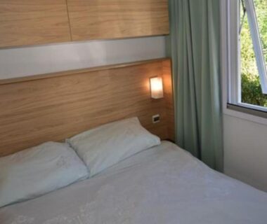 Intérieur de chambre avec lit double et lampe dans le mobil-home 4 personnes du camping 5 étoiles