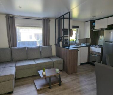 Salon avec canapé et kitchenette dans le Mobil-home 40m2 au calme, plage, piscine, forêt