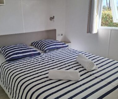 Chambre avec lit double et serviettes dans le mobil-home 447 du camping Siblu 4 étoiles