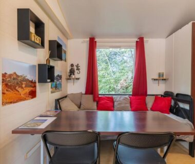 Coin repas avec table chaises banquette et rideaux rouges dans le Mobil-home