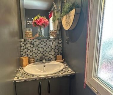 Salle d'eau avec lavabo miroir mosaïque et bouquet de fleurs du mobil-home 5 personnes à louer