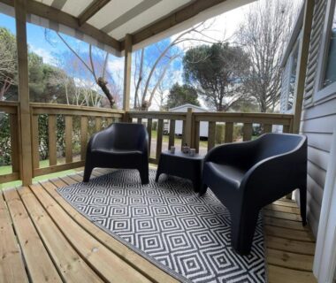 Terrasse couverte avec fauteuils et table sur plancher en bois du Mobil home 532 au bord du Lac de Biscarrosse
