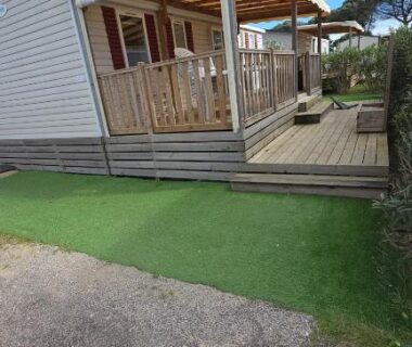Terrasse couverte en bois avec pelouse au mobil-home