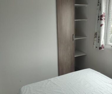 Chambre avec lit armoire et étagères dans le mobil home