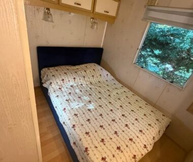 Chambre avec lit double et rangements près de la fenêtre dans le Mobil-home