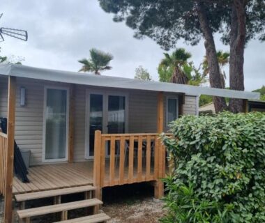 Terrasse en bois et façade entourées de pins du Mobil-home 6-8 pers 3ch-2sdb Camping Les Sables d'Or