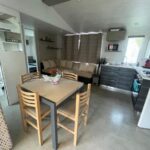 Séjour avec table canapé et kitchenette du Mobil home 6-8pers Le lac des rêves