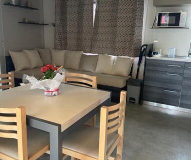 Séjour avec canapé, table à manger et kitchenette dans le mobil home Le lac des rêves