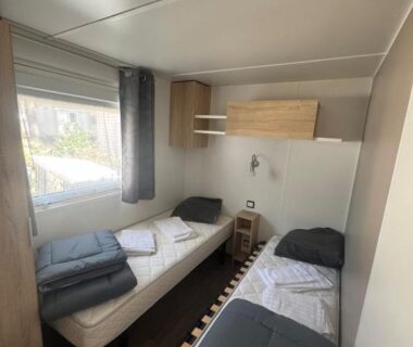 Chambre avec deux lits simples et rangement dans le mobil home 6 à 8 personnes