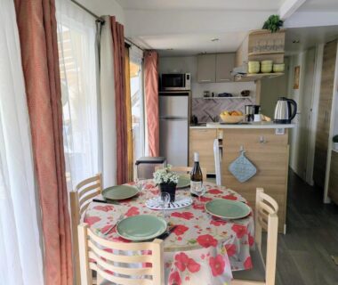 Intérieur avec table dressée et kitchenette dans le Mobil home 6 à 8 personnes climatisé