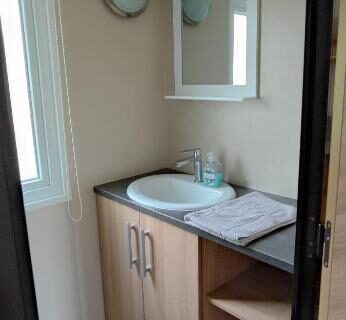 Salle d'eau avec lavabo meuble vasque et miroir du Mobil-home 6 couchages