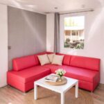 Intérieur salon avec canapé rouge table basse et tapis dans le Mobil-home 6 pers Terrasse couverte Calme