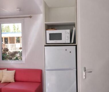 Coin salon avec canapé rouge et réfrigérateur du Mobil-home 6 pers Terrasse couverte Calme