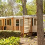 Terrasse en bois et mobil-home parmi les pins du Mobil-home 6 pers tout confort Clim piscine et animations