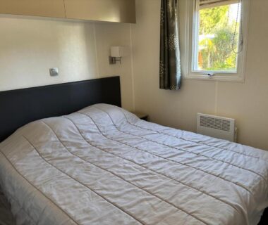 Chambre avec lit double et fenêtre donnant sur végétation dans le mobil home 6 personnes