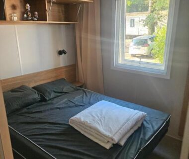 Intérieur chambre avec lit double et étagères dans le mobil home 6 personnes