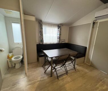 Séjour avec coin repas et toilettes visibles dans le Mobil home 6 personnes