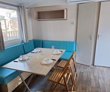 Coin repas avec banquette bleue et table dressée dans le Mobil home 6 personnes