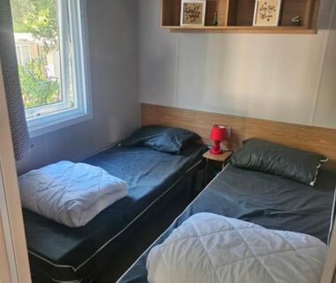 Chambre avec deux lits simples et fenêtre dans le mobil home 6 personnes