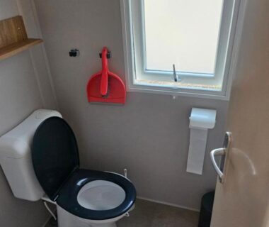 WC intérieur avec lunette noire et fenêtre dans le mobil home 6 personnes