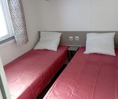 Chambre avec deux lits simples et fenêtre dans le mobil-home 6 personnes Camping 4 etoiles