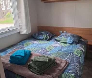 Chambre avec lit et serviettes dans le mobil home 6 personnes Camping SIBLU le Bois de Bayadène