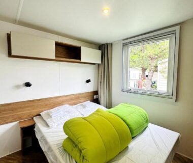 Intérieur chambre avec lit et fenêtre dans le mobil-home six personnes Clim Camping Mar Estang