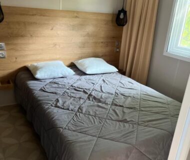 Chambre avec lit double et tête de lit en bois dans Mobil home 6 personnes à 400m de la mer