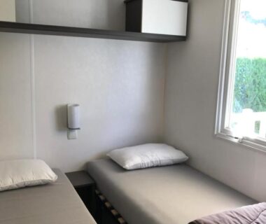 Chambre avec deux lits simples et fenêtre dans le mobil home 6 personnes du camping 5*