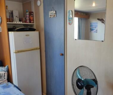 Intérieur avec kitchenette réfrigérateur et ventilateur dans le Mobil home 6 place a 900 mètres de la plage