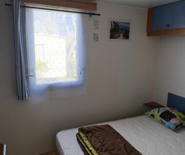 Chambre avec lit et fenêtre dans le Mobil home 6 place a 900 mètres de la plage
