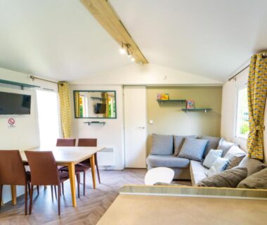 Séjour avec canapé et coin repas dans le mobil-home 6/8 personnes du Camping Siblu Domaine de Dugny