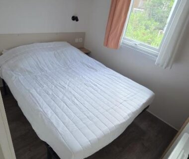 Chambre avec lit double et rangements près de la fenêtre dans le mobil-home