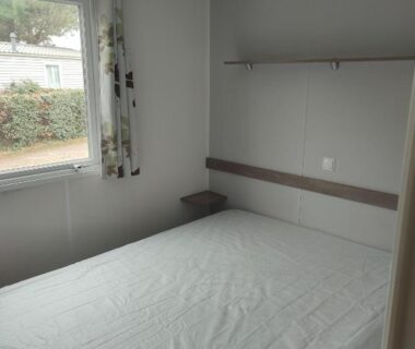 Chambre avec lit double et fenêtre donnant sur l'extérieur dans le Mobil home