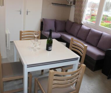 Coin repas avec table chaises et canapé près de la fenêtre dans le Mobil-home