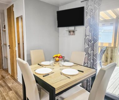 Salle à manger avec table dressée et baie vitrée du Mobil home 8 personnes Confort & Tranquillité