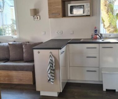 Intérieur avec coin salon et cuisine équipée dans le mobil home Amira 3 Trigano