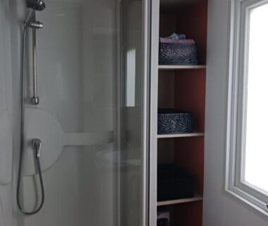 Salle d'eau avec cabine de douche et étagères dans le mobil home CARNAC