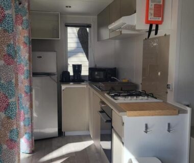 Intérieur cuisine avec plaque de cuisson réfrigérateur et poubelle dans le mobil home Camping La Marine