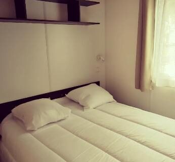 Chambre avec lit double et fenêtre du Mobil home Camping Les Embruns 4 étoiles