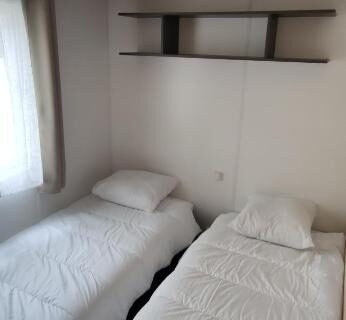 Chambre avec deux lits et étagère dans le mobil home du Camping Les Embruns 4 étoiles